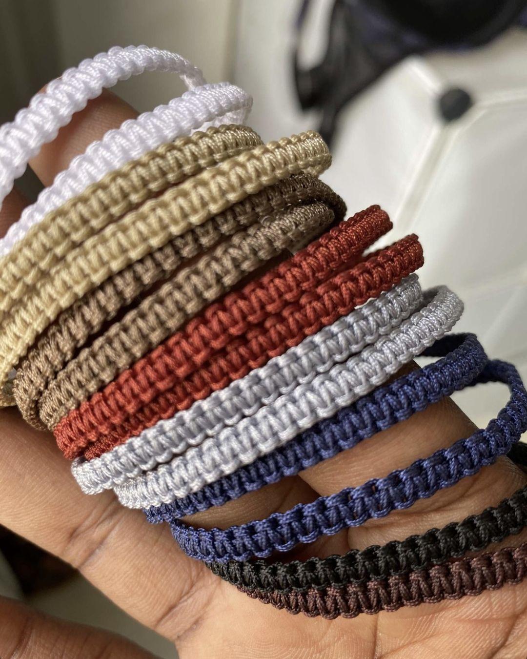 Main dans la verdure portant le bracelet tissé sombre