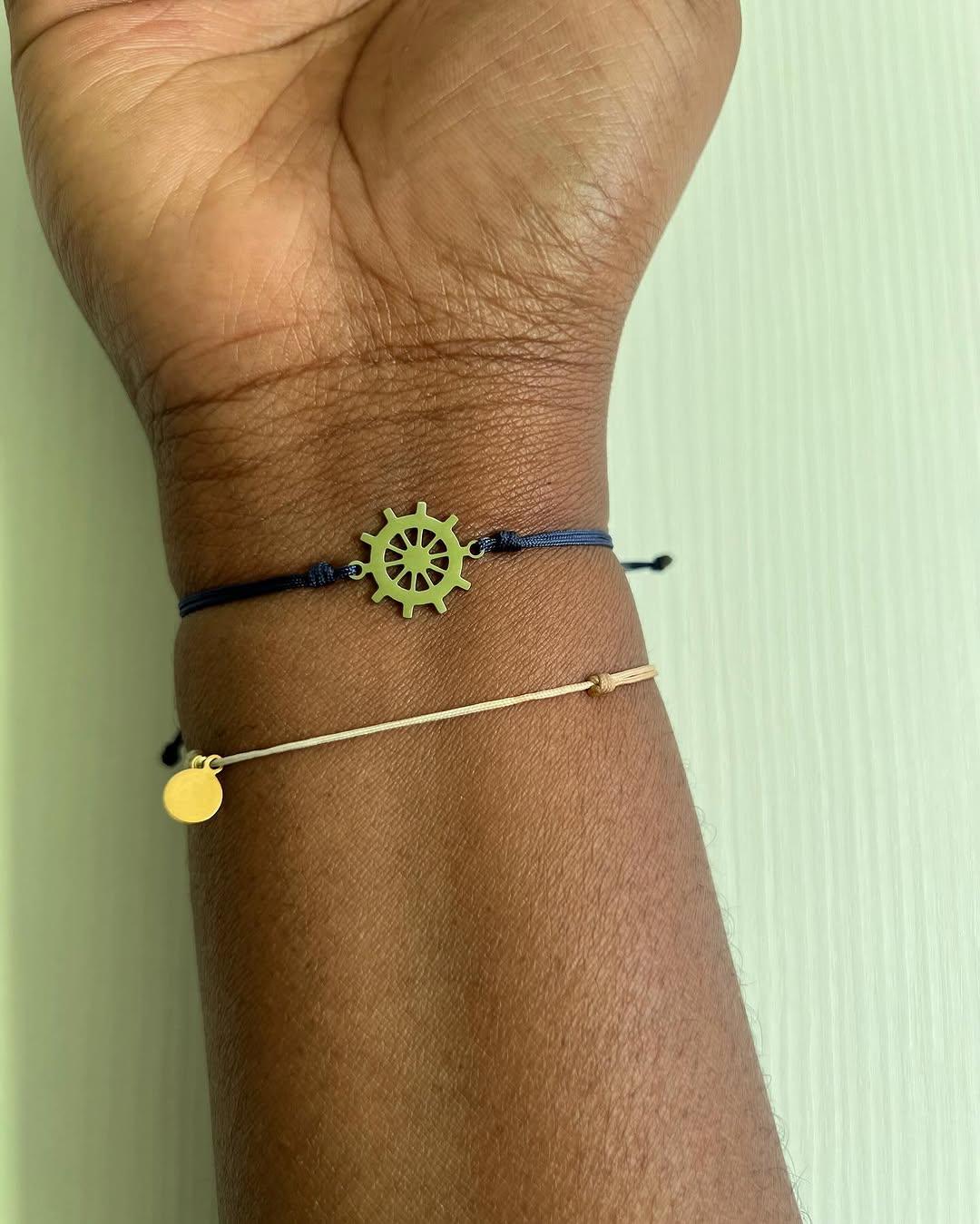 Bracelet gouvernail doré porté au poignet