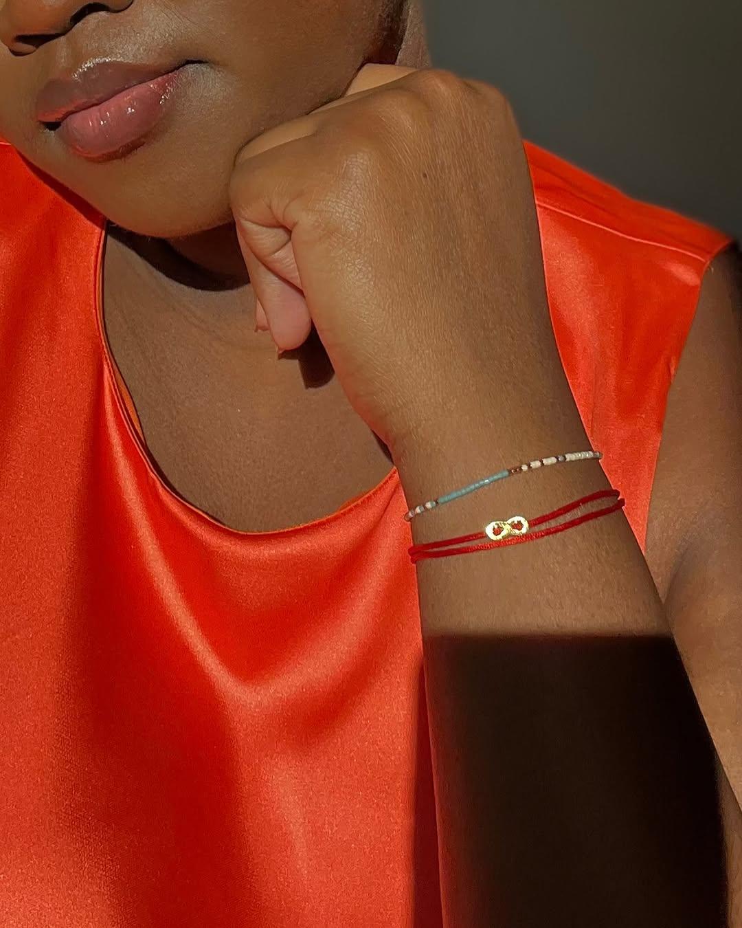 Bracelet infini sur cordon rouge porté au poignet